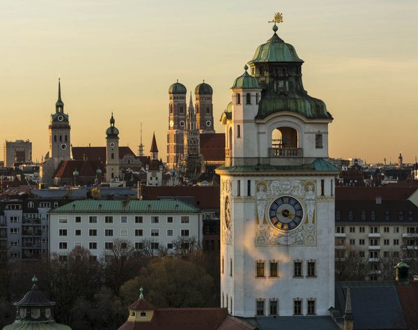 Überblick über die Dächer Münchens mit den verschiedenen Kirchtürmen im Sonnenuntergang.